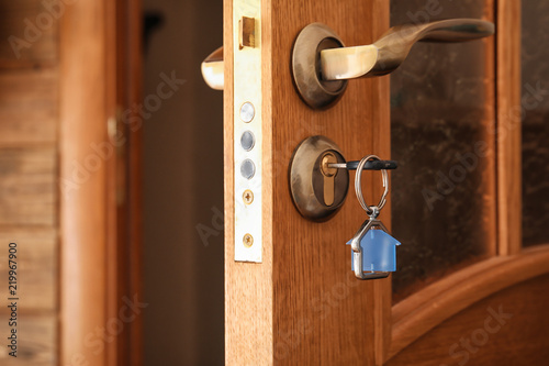 Key with house-shaped trinket in door lock, closeup