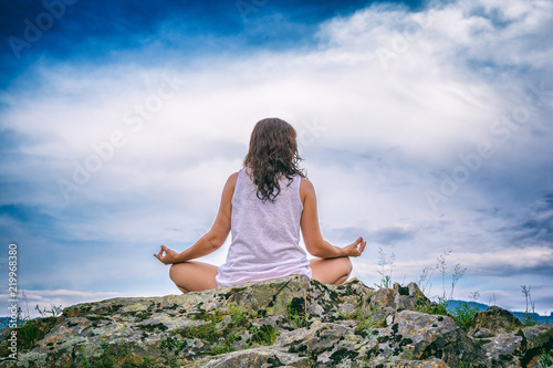 young woman meditating on a rock. tranquility and privacy in the mountains. Travel and tourism. Closeup