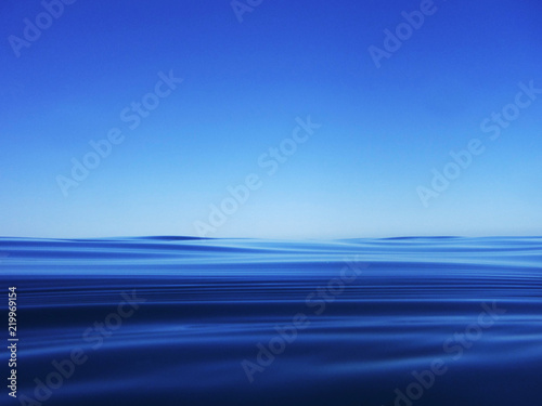 The surface of a bright blue sea under a blue sky. Minimalism