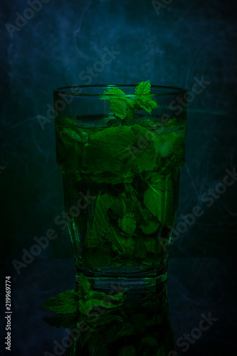 Glass of fresh mint tea on a dark background. Light painting. Copy space.
