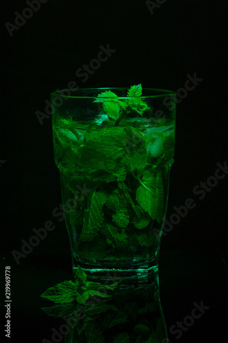 Glass of fresh mint tea on a dark background. Light painting. Copy space.