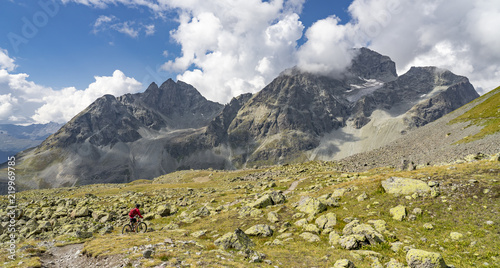 active senior woman, riding her e-mountainbike on the famous Suvretta Loop trail, high above Saint Moritz, Engadin, Switzerland photo