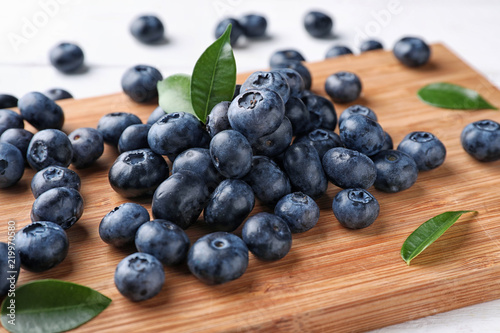 Board with ripe blueberries on table, closeup