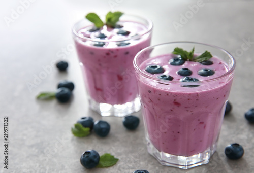 Glasses of tasty blueberry smoothie on light table
