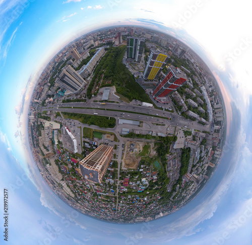 Aerial view of square in the city with roundabout traffic, streets and buildings with green trees in the view of the part of the planet from panorama photo with three colored houses