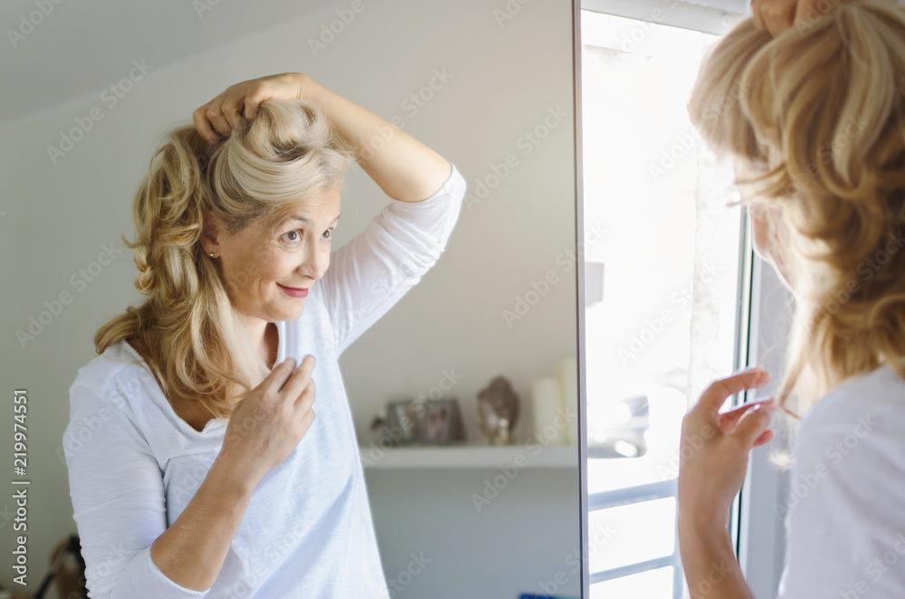 Woman cheking her hair in front of mirror Woman cheking her hair in front of mirror
