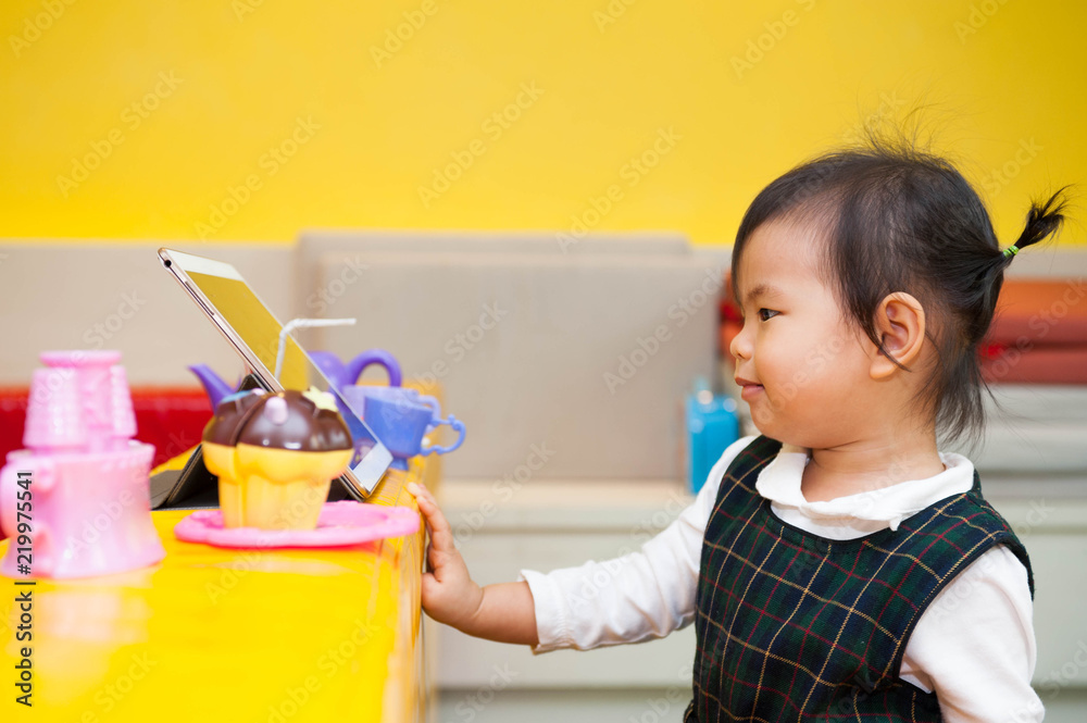 Asian baby girl watching a tablet with toys placed nearby Asian baby girl watching a tablet with toys placed nearby
