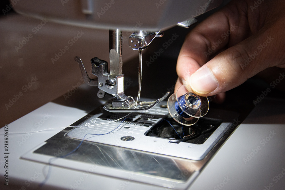 Close Up of Hands Replacing the Spool of Thred on a Sewing Machine