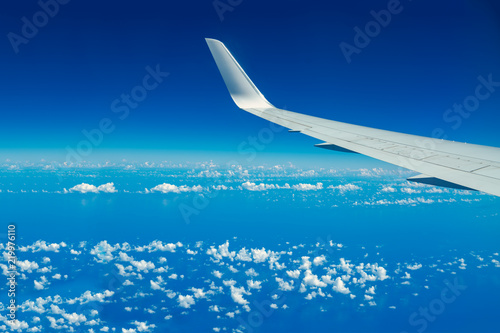 Looking through aircraft window during flight. Aircraft wing over blue skies and white clouds.Copy space.