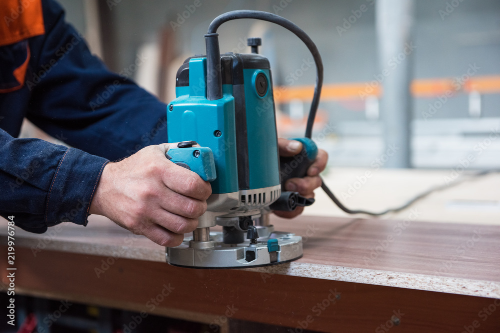 Fototapeta premium Furniture production or craft concept: worker polishing the wood surface of furniture part with polish machine