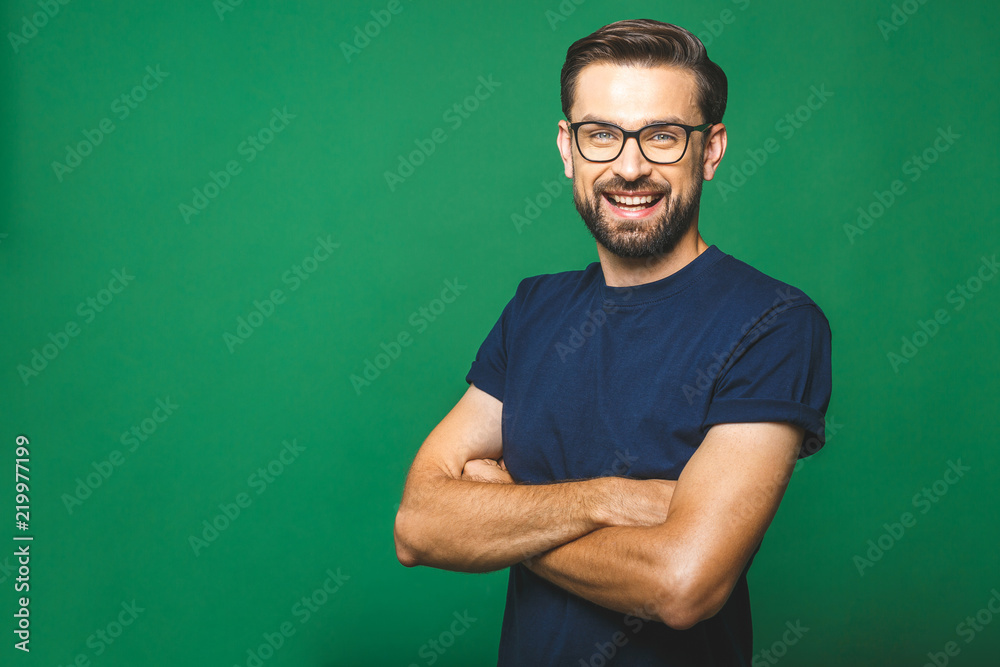 A portrait of young handsome man in casual isolated on green background with glasses. - obrazy, fototapety, plakaty 