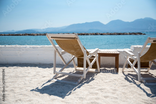 Two Deckchairs In Tropical Beach at quiet sea.