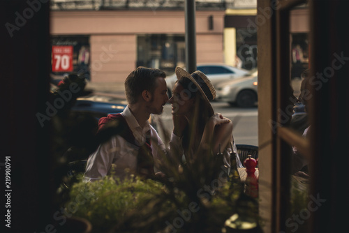 A loving couple is sitting at a table in a cafe near the road © Вадим Михеев