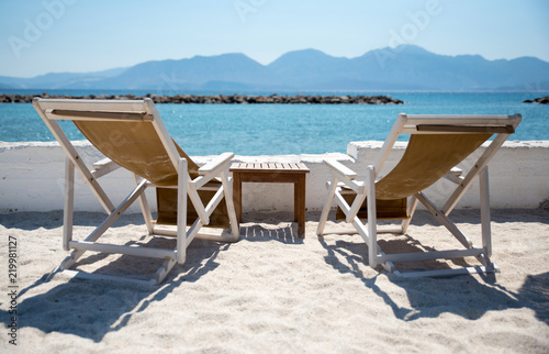 Two Deckchairs In Tropical Beach at quiet sea.