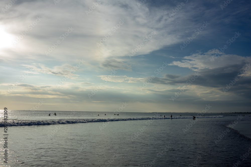 people on beach in water at sunset