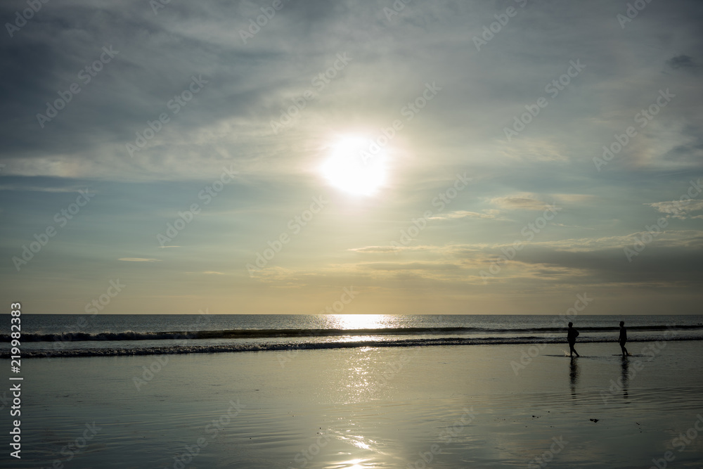 Naklejka premium people on beach in water at sunset