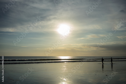 people on beach in water at sunset