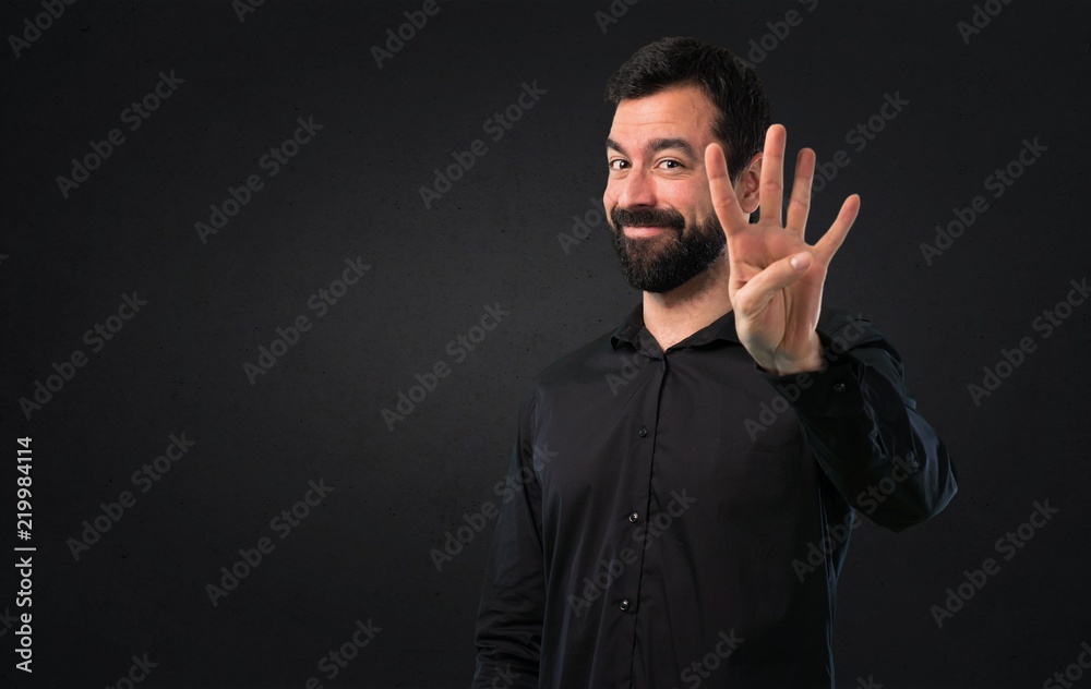 Handsome man with beard counting four on black background Handsome man with beard counting four on black background