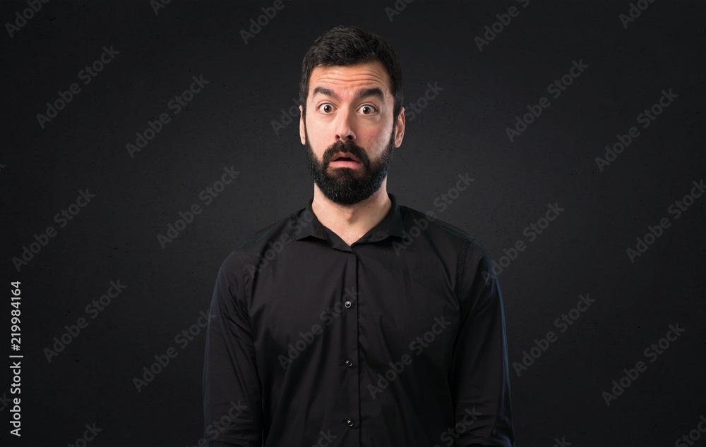 Handsome man with beard making surprise gesture on black background Handsome man with beard making surprise gesture on black background