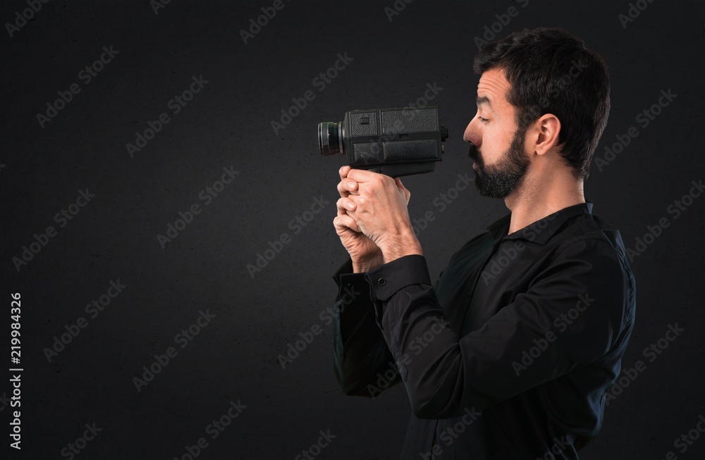 Handsome man with beard filming on black background Handsome man with beard filming on black background