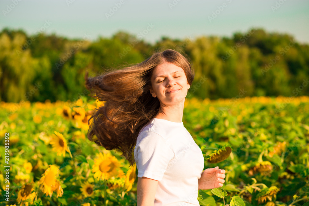 Summer portrait of happy young woman in white with flying hair in sunflower field Summer portrait of happy young woman in white with flying hair in sunflower field