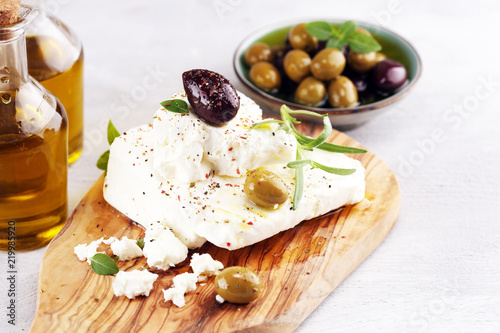 Greek cheese feta with herbs and olives on rustic table.