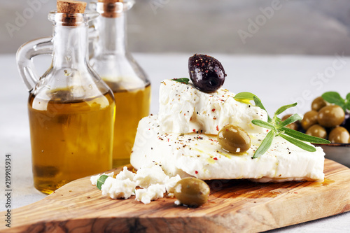 Greek cheese feta with herbs and olives on rustic table.