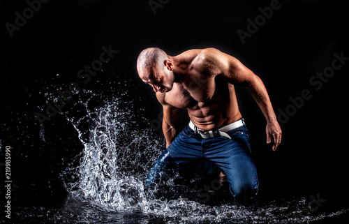 very muscular handsome athletic man striking with a hand on water