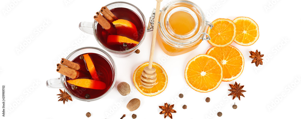 Hot red mulled wine, bee honey, slices of oranges and spices isolated on white background. Wide photo.