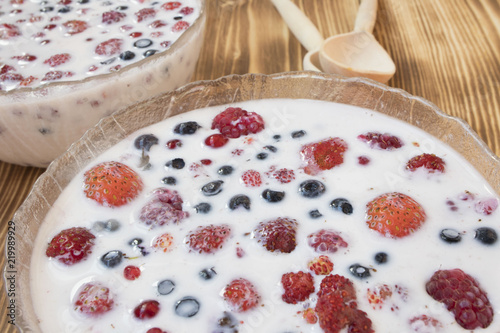 berries in milk on wooden background, healthy food concept photo