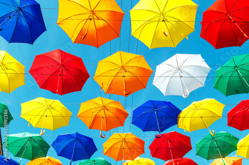 Multicolored floating umbrellas against the blue sky.