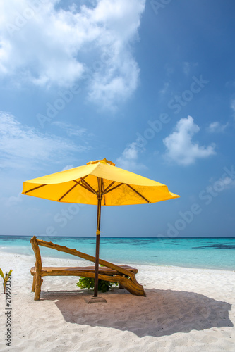 Fototapeta Naklejka Na Ścianę i Meble -  A sun lounger and a beach umbrella on a deserted beach; perfect vacation concept; blue sky; amazing sea