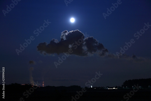 Elektrownia, fabryka w nocy w świetle księżyca w pełni nad chmurą pary.