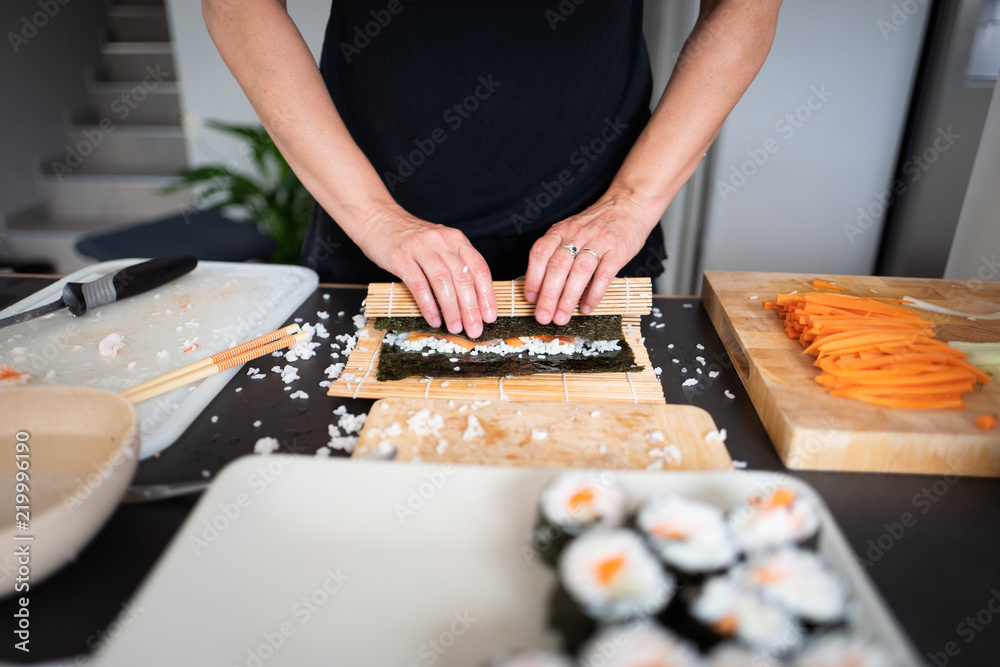 Fototapeta premium Woman making at home Japanese sushi rolls