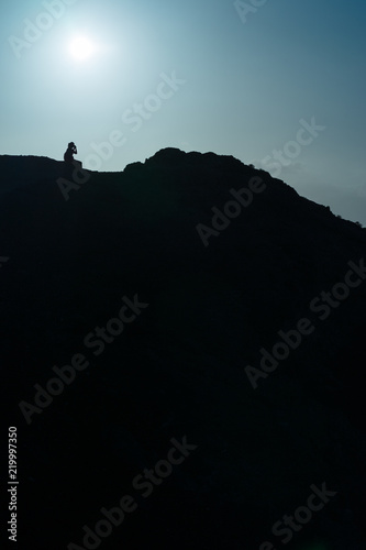 Silhouette of a girl taking a picture on the top of a mountain  Lanzarote  Spain