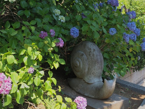 snaol stone sculpture in hydrangea garden