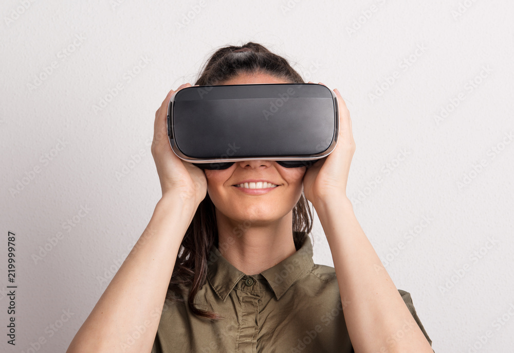 Portrait of a young beautiful woman with VR goggles in studio. Portrait of a young beautiful woman with VR goggles in studio.