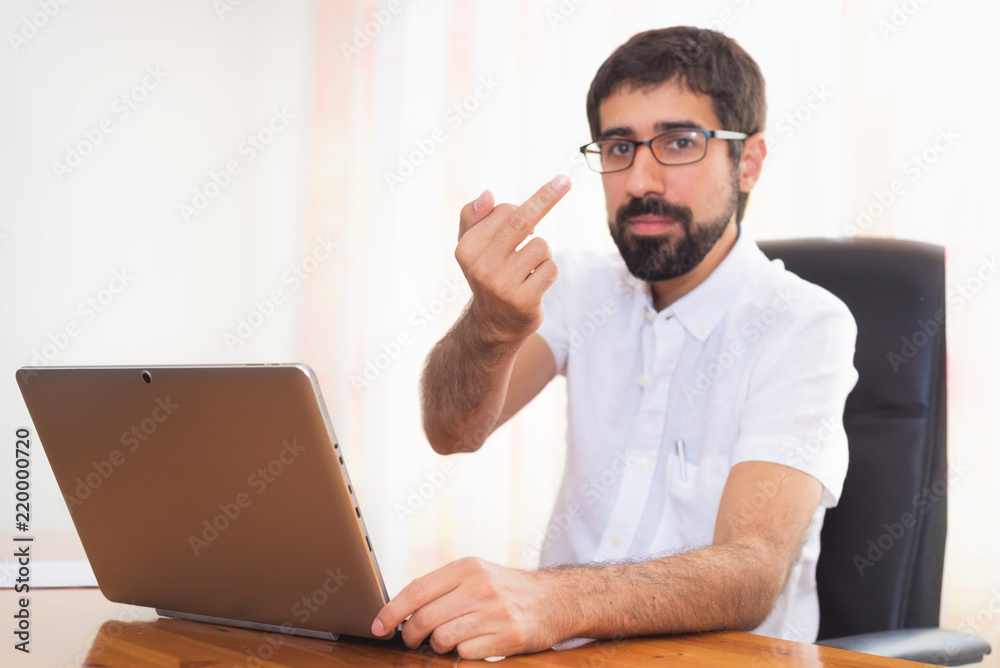 Angry expression young bearded man working at the office Angry expression young bearded man working at the office