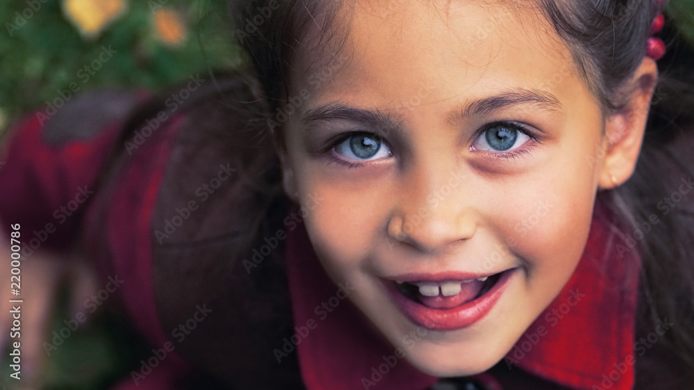Cute adorable toddler girl portrait with autumn leaves on the ground at the background. Child outdoor in park or forest. Cute adorable toddler girl portrait with autumn leaves on the ground at the background. Child outdoor in park or forest.