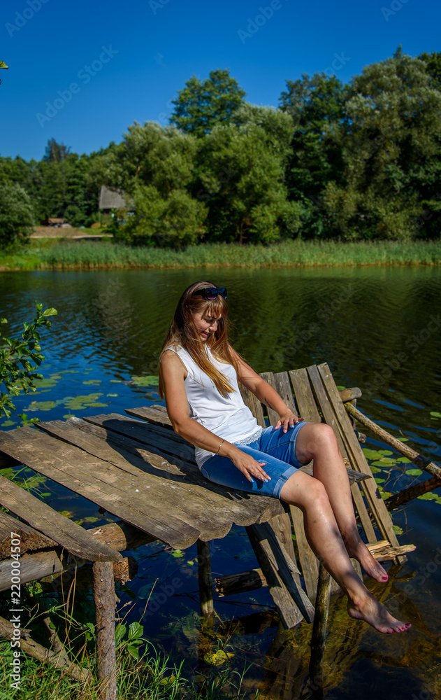 Woman on the sea, the lake. Cute woman on a half-ruined wooden bridge over blue water on a sunny day
