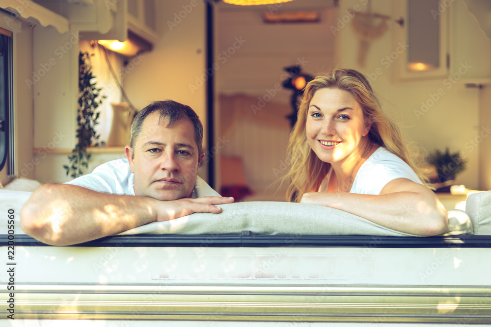 Obraz premium Happy couple of tourists sitting in a camper van.