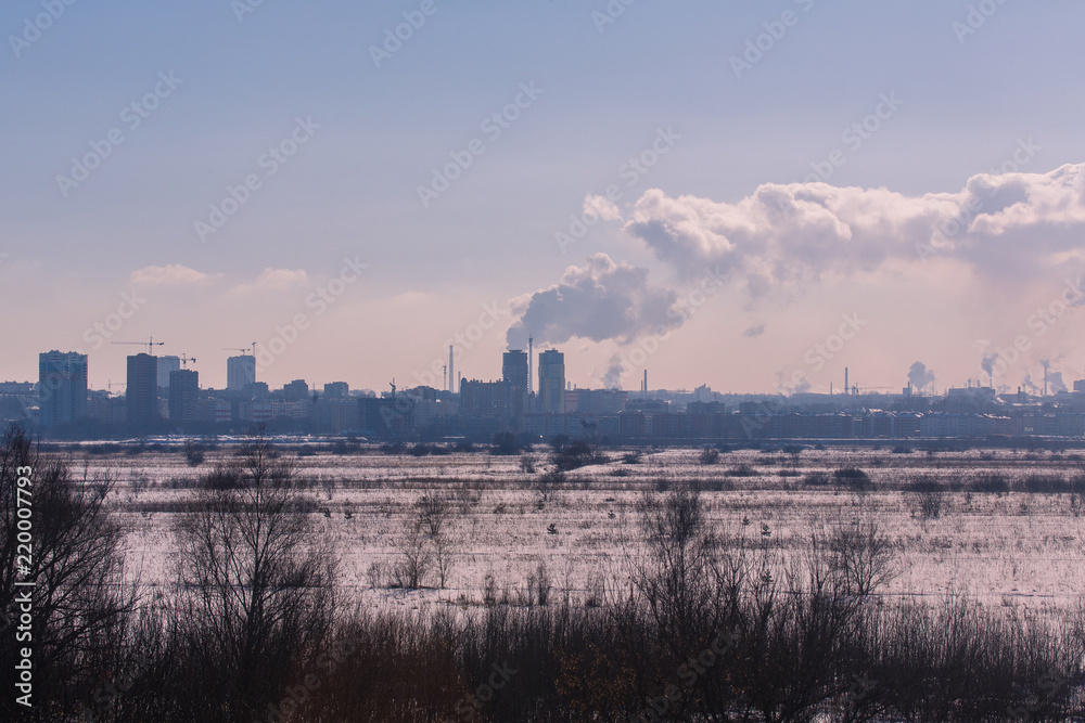 Winter landscape industrial outskirts of the city. Silhouettes of buildings and cranes.