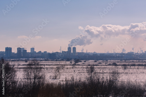 Winter landscape industrial outskirts of the city. Silhouettes of buildings and cranes.