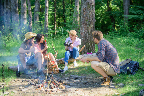 Company having hike picnic nature background. Tourists hikers sit on log relaxing waiting picnic snack. Picnic with friends in forest near bonfire. Hikers relaxing during snack time. Summer picnic