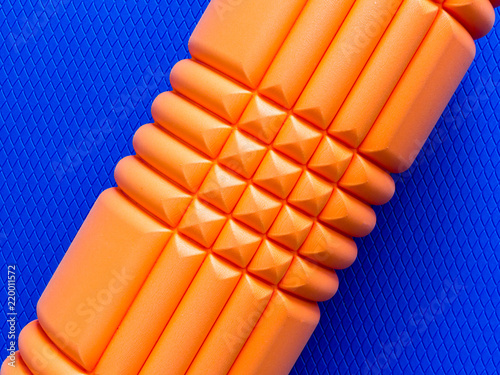 Orange foam roller on blue background