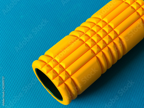 Yellow foam roller on blue background