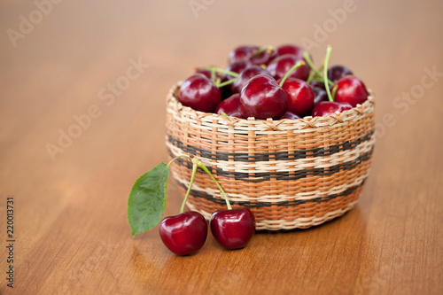 Red Ripe Cherries in a basket on a wood table photo