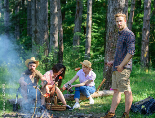 Tourists sharing thoughts about hike sit on log. Company having hike picnic nature background. Summer tradition. Picnic with friends in forest near bonfire. Hikers sharing impression of walk forest