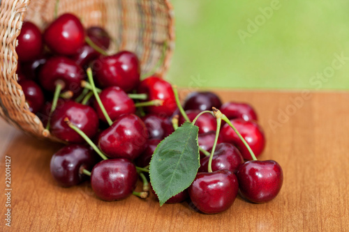 Red Ripe Cherries spilling from basket on a wood table photo