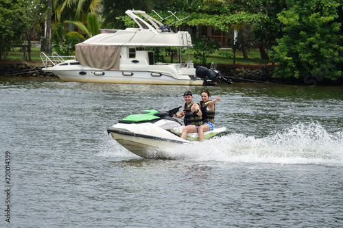 Happy young couple with thumbs up enjoying and having fun riding on a jet ski. Tropical coast of Sri Lanka